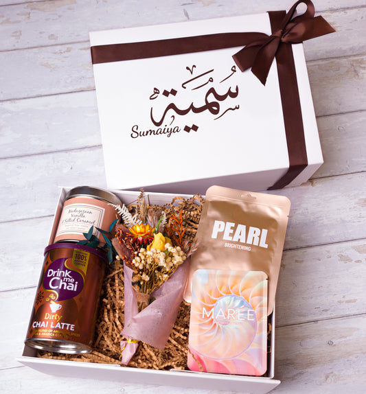 Relaxation gift box with scented candle, face mask, chai latte, flowers, and eye mask